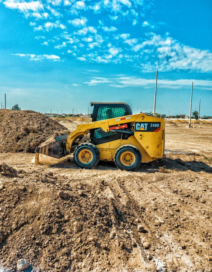 Skid steer loader at a daytime construction site with blue sky backdrop.